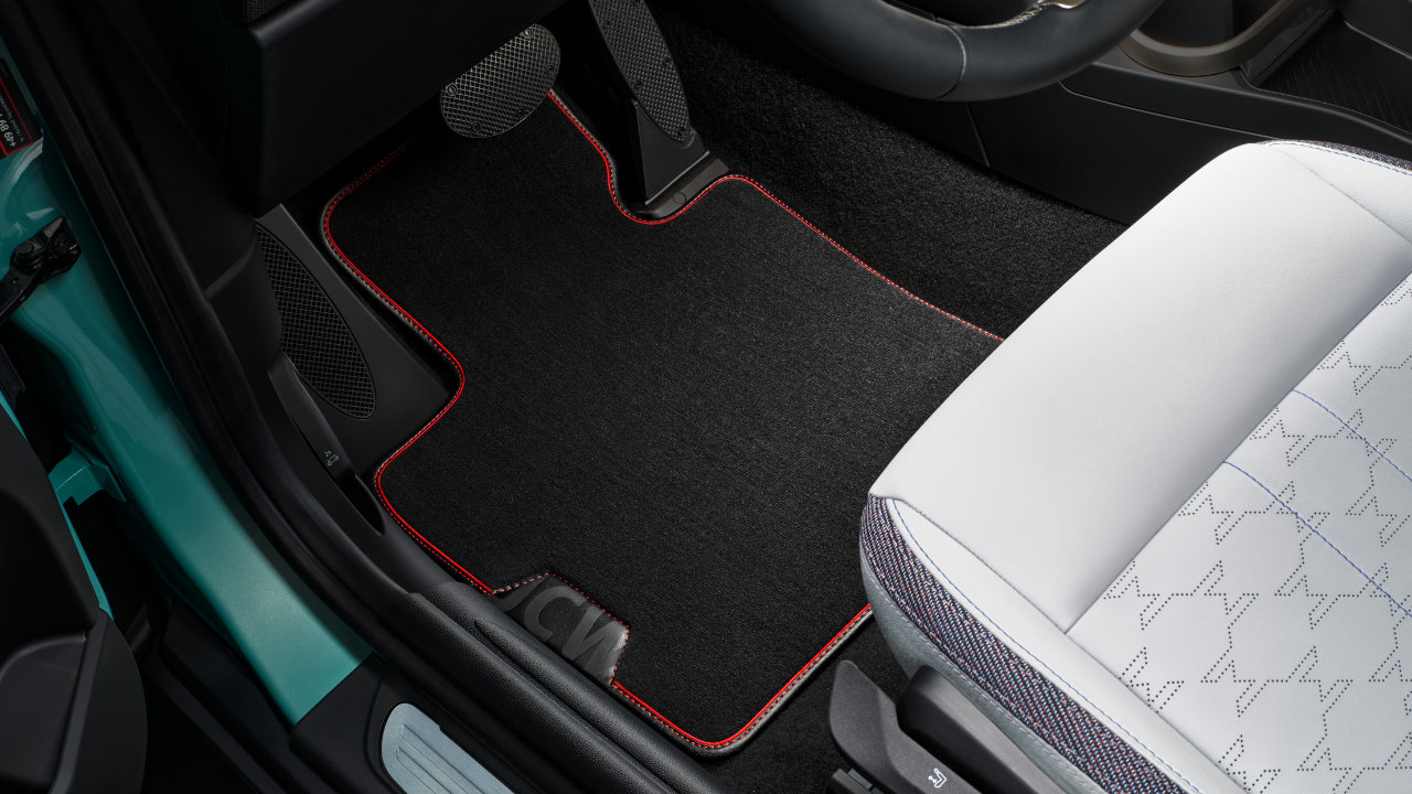 A MINI JCW floor mat sits on the floor of the driver's side of a MINI JCW.
