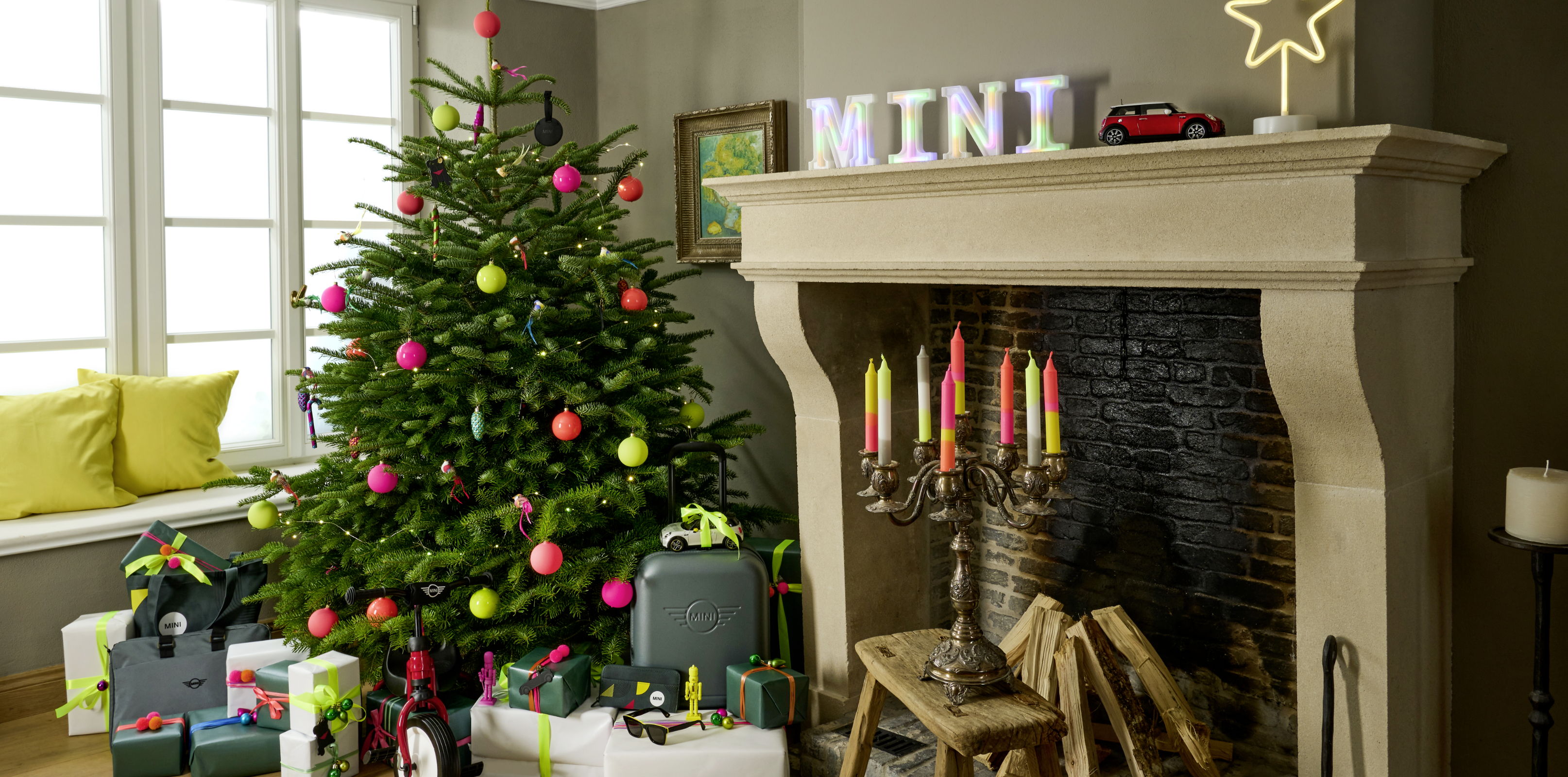 MINI gifts sit beneath a Christmas tree next to a hearth